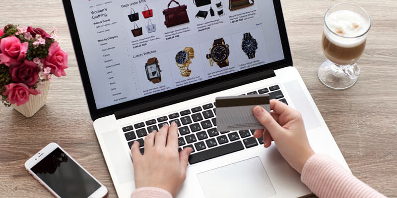 Woman purchasing a watch at laptop with credit card in hand