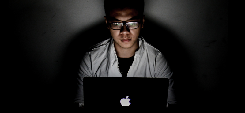 Man browsing an Apple Mac in the dark