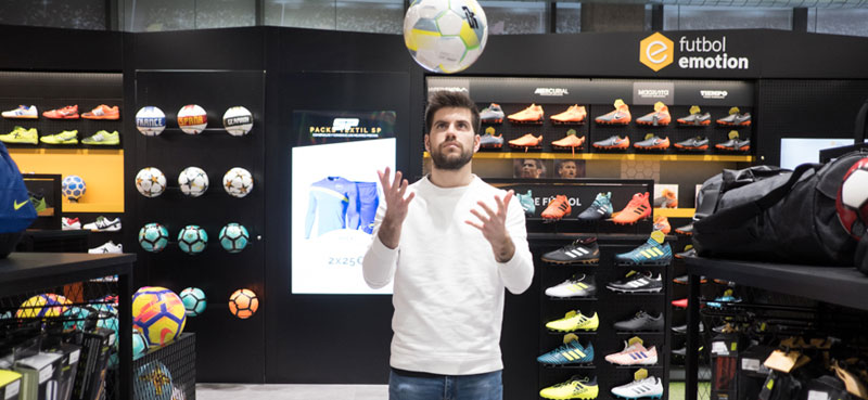 Footballer Gerard Pique throwing a ball in his hands whilst in a trainer shop