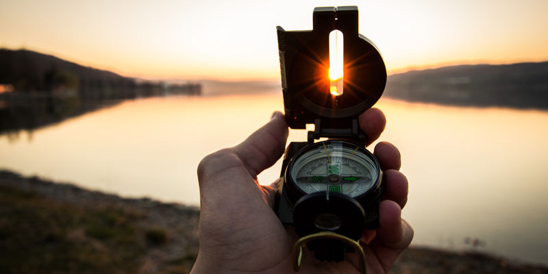 A compass held aloft against a natural backdrop