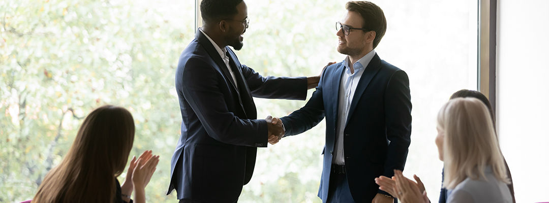 Happy African American business leader shaking hands with promoted employee. Boss hiring new team member, welcoming worker, expressing recognition for good work. Audience team clapping hands