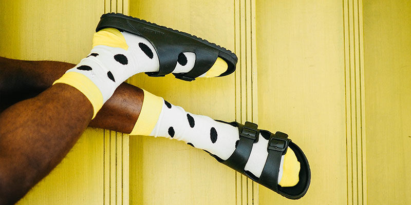 Man with spotty socks and black sandals with yellow background