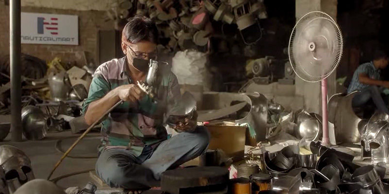 Man spray painting helmets in workshop