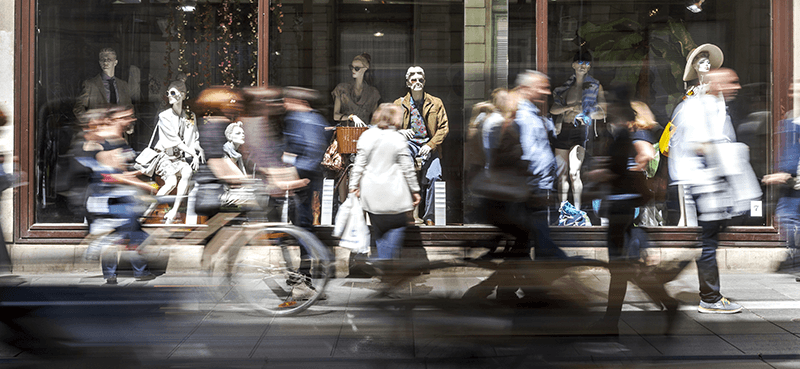 A busy high street with mannequins lining a shop window