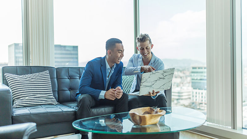 two men smiling at laptop screen