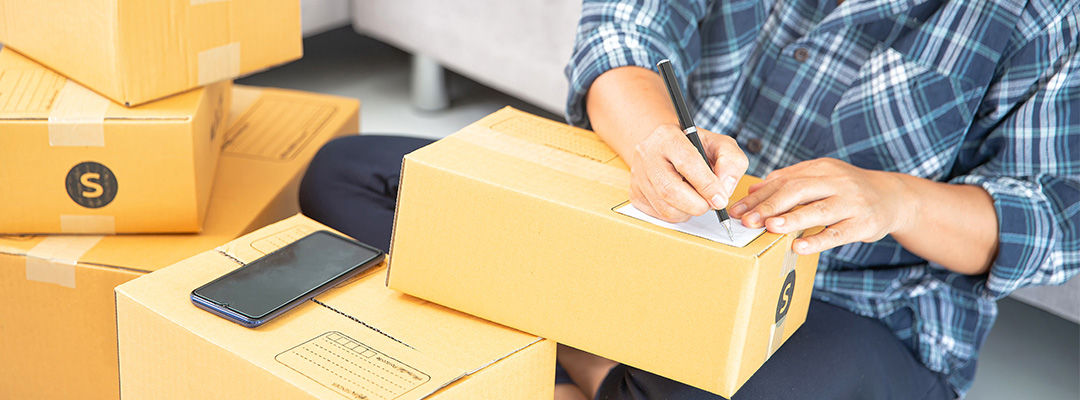 woman writing on brown box