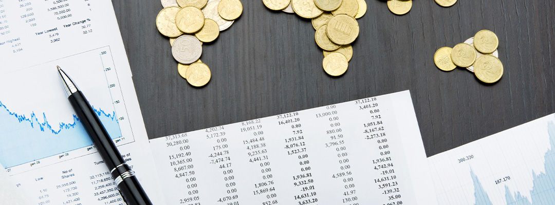 coins arranged on a desk with a pen on it