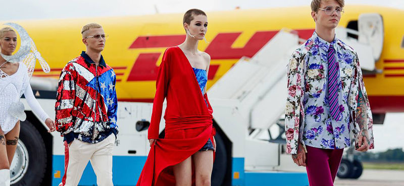 Four models posing in front of a DHL plane