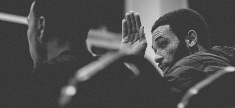 Black and white photo of man waving to man he's sitting next to