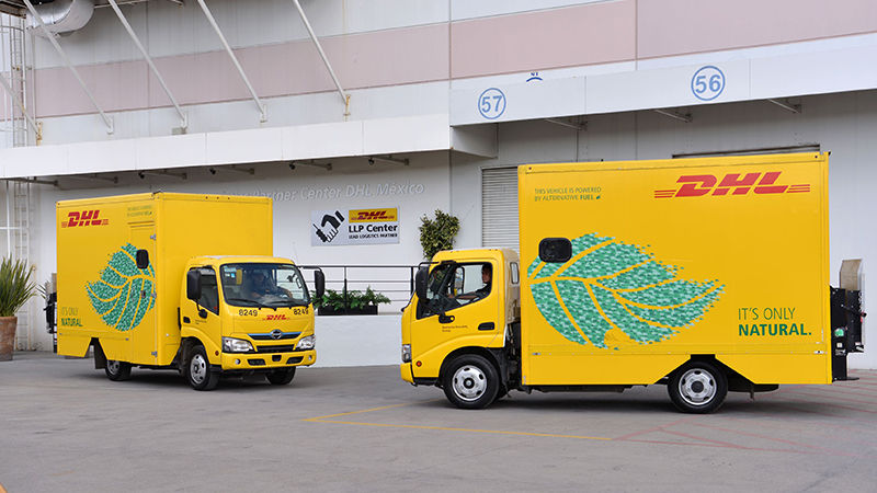 two DHL vans parked in a parking lot