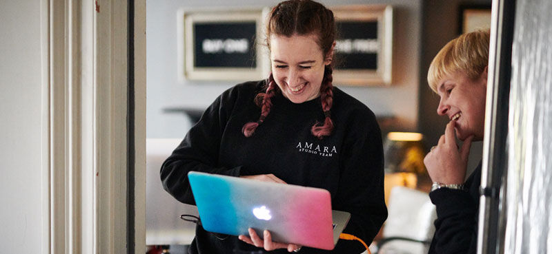 Amara employees laughing and working on a laptop