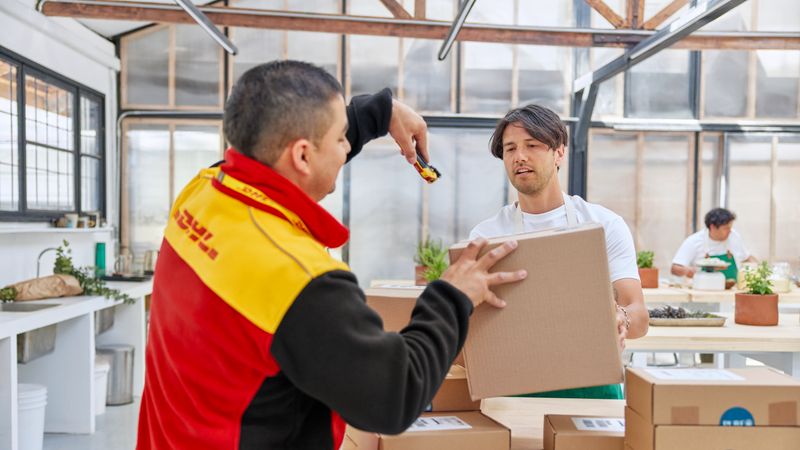 dhl employee is scanning parcels for pick up from an e-commerce start up