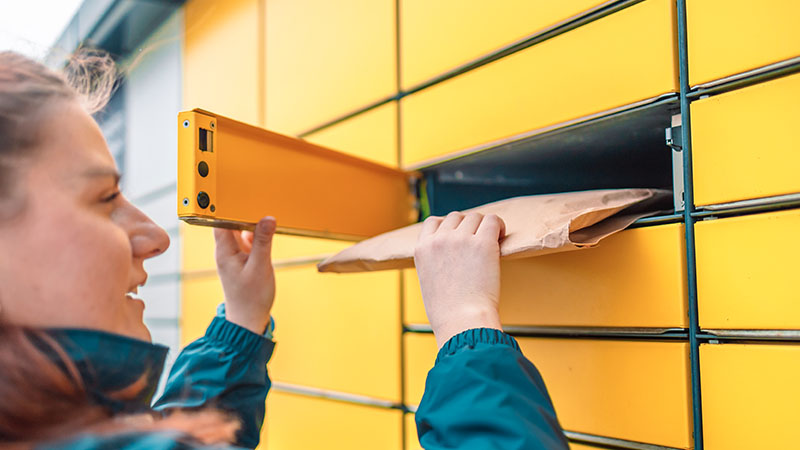 woman placing parcel in parcel locker