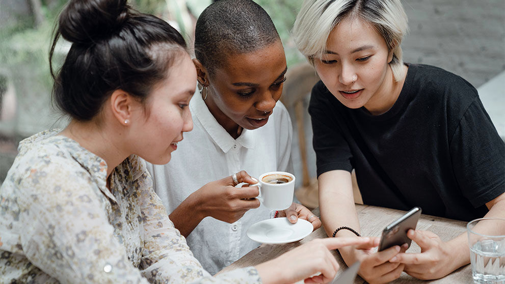 three women looking at mobile screen