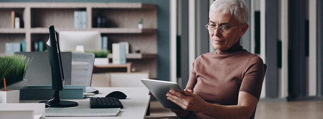 Concentrated senior businesswoman using digital tablet while working in the office