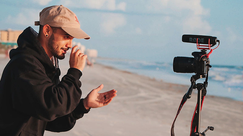 man recording a video on a beach