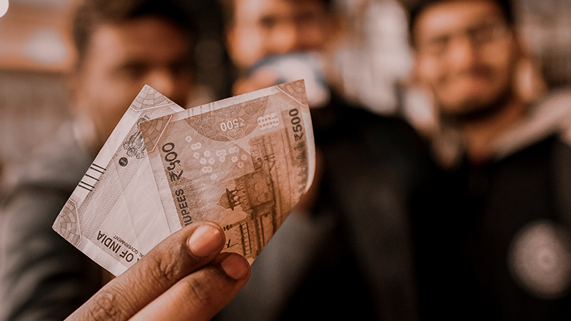 man holding Rupee bank notes