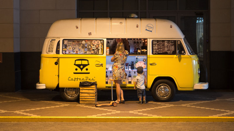 Woman and boy standing outside yellow food van