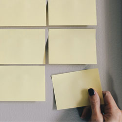 hand putting up yellow post-its