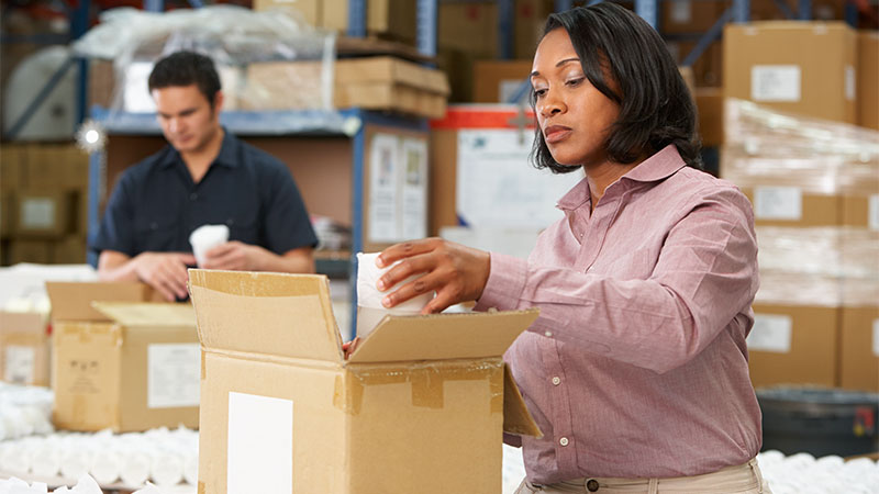 woman packing items into brown box