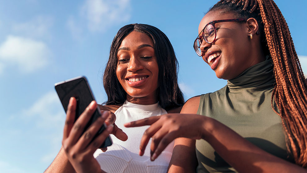 two women smiling at mobile phone screen