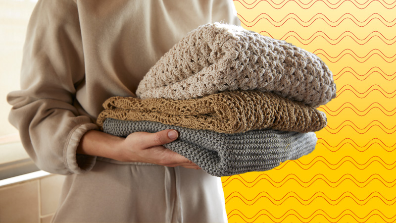 holding a folded pile of jumpers