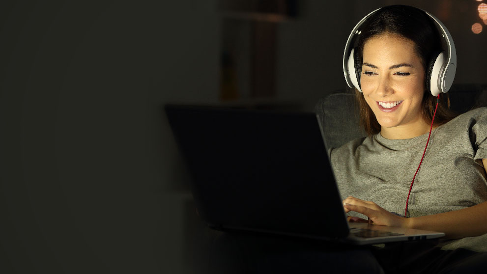 Woman in headphones smiling at laptp