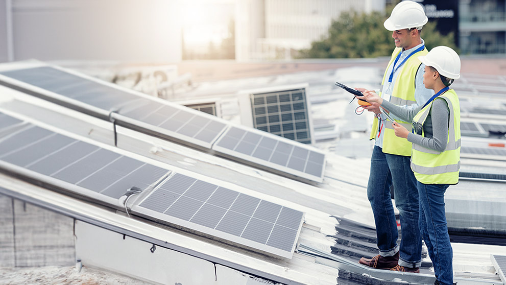 man and woman in hard hats looking at solar panels