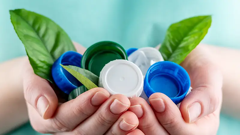 hand holding plastic milk bottle tops