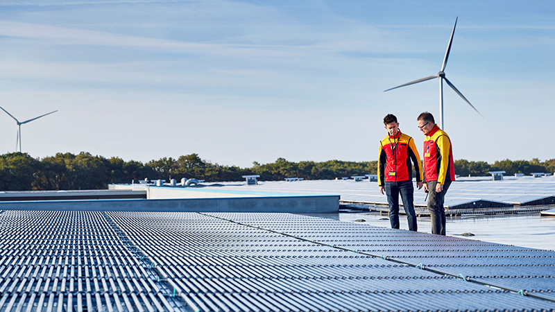 two DHL employees looking at solar panels