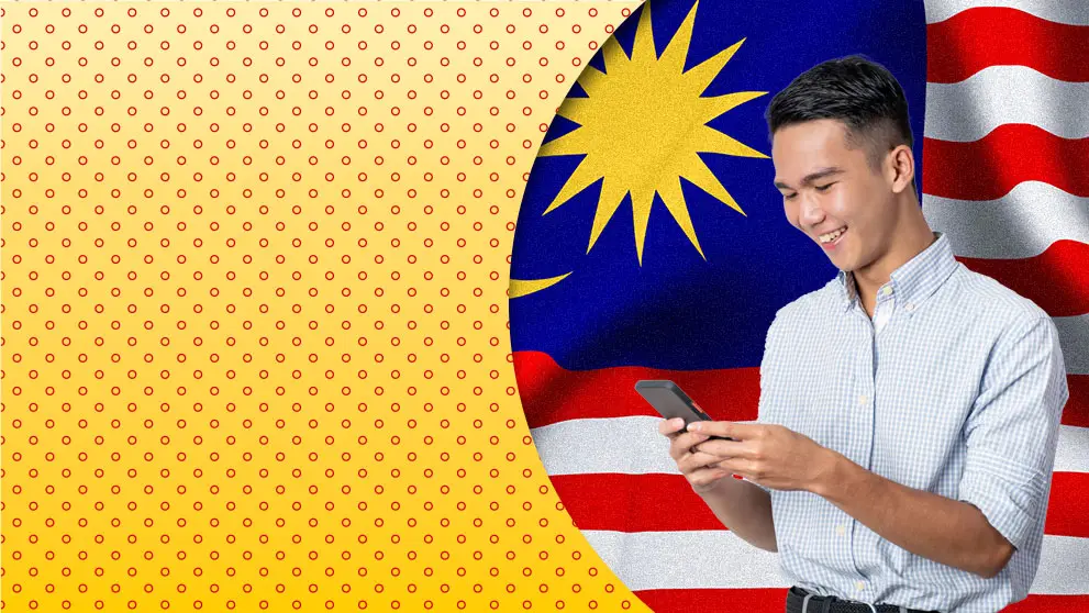 Malaysian  man smiling at mobile phone screen