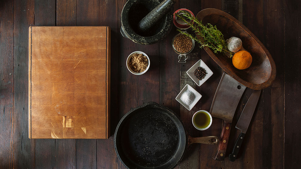 Wooden table with brown book on the left, with cooking ingredients on the right