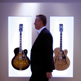 Man walking past 2 guitars pinned to the wall