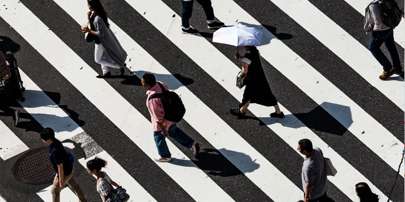 people walking across a black and white street