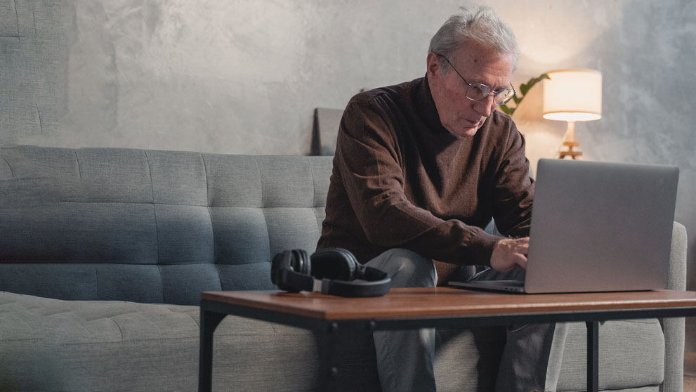 old man typing on laptop