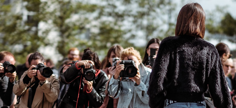 People photographing a woman in a black coat
