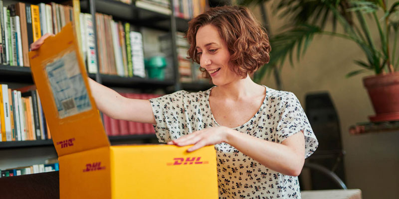 Happy woman opening DHL parcel 