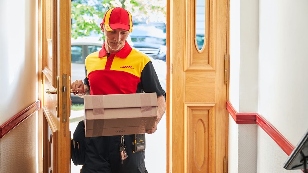 DHL employee walks in the front door carrying a parcel containing Pakistani footwear