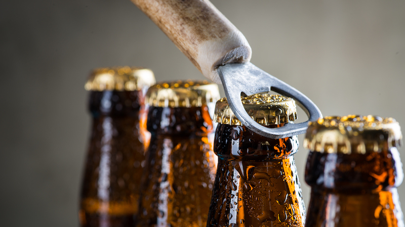 Brown ice cold beer bottles with water drops and old opener