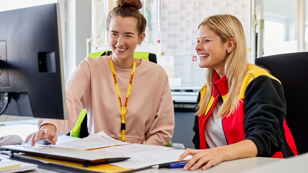 DHL Employees laughing while looking at a computer screen